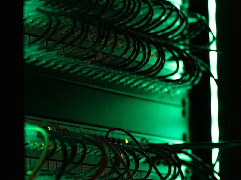 Patchfeld in einem Netzwerkschrank, von grünem Licht beleuchtet